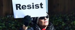 A woman holds a placard reading 'Resist'