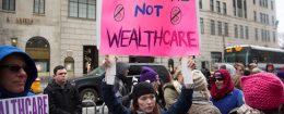 Health care activists lift signage promoting the Affordable Care Act