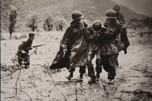 Kapaun, right, and a doctor help an exhausted soldier in Korea.