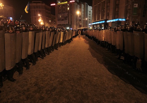 A journalist walks between lines of Ukrainian riot policemen