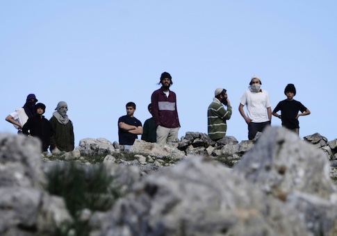 Israeli settlers of Yitzhar take position during a confrontation with Palestinians