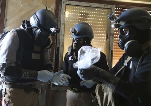 A U.N. chemical weapons expert holds a plastic bag containing samples from one of the sites of an alleged chemical weapons attack in Ain Tarma