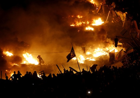 Anti-government protesters stand behind burning barricades in Kiev's Independence Square