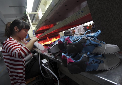 A Chinese worker labors in a factory making sports shoes