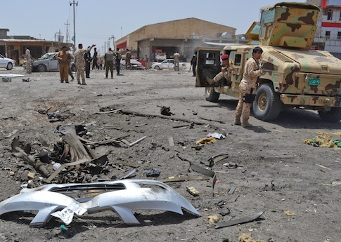 Civilians and security forces inspect the site of a suicide bomb attack in Tuz Khormato, 130 miles north of Baghdad, Iraq