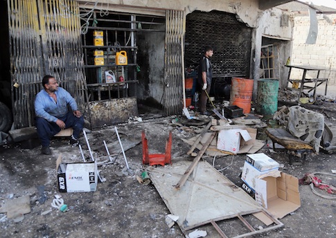 Civilians inspect the aftermath of a car bomb explosion at an industrial area