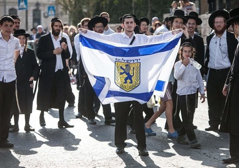 An ultra orthodox Jewish man holds a flag with the symbol of the Jerusalem monicipality, at the scene of the digger attack. One man was killed and six other were wounded as a 19 year-old Palestinian man driving a digger, went on a rampage in the center of Jerusalem.