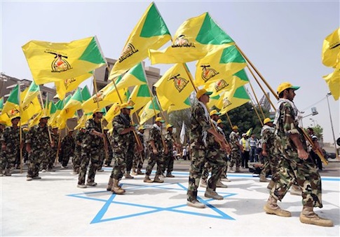 Supporters of Iraqi Hezbollah brigades marching in military uniforms step on a representation of an Israeli flag