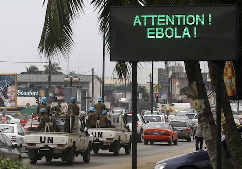 A U.N. convoy of soldiers passes a screen displaying a message on Ebola on a street in Abidjan