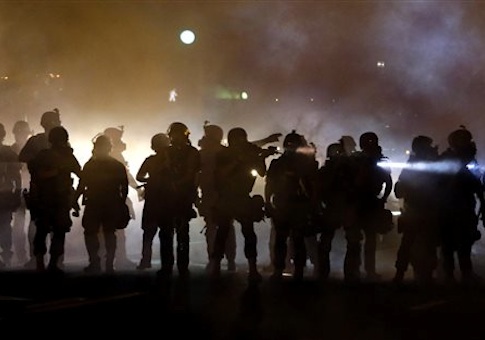 police walk through a cloud of smoke as they clash with protesters in Ferguson, Mo.