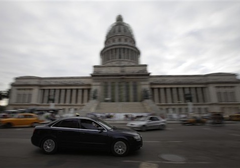 An automobile drives by the Capitol in Havana, Cuba