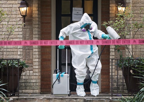 A member of the CG Environmental HazMat team disinfects the entrance to the residence of a health worker at the Texas Health Presbyterian Hospital who has contracted Ebola in Dallas, Texas