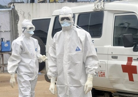 Health workers wearing protective gear wait to carry the body of a person suspected to have died from Ebola, in Monrovia, Liberia