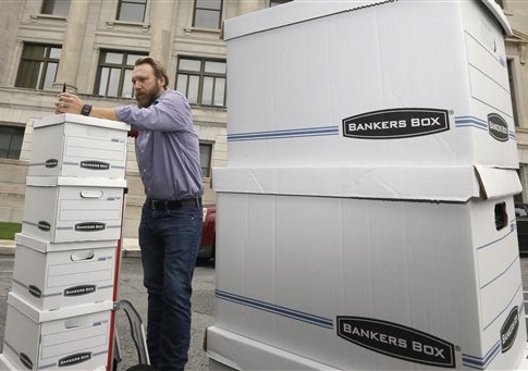 Greg Hale leans on boxes of petitions signed by supporters of a state minimum wage increase at the Arkansas state Capitol in Little Rock, Ark.