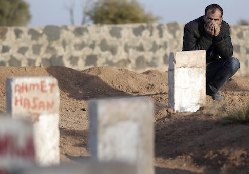 A Kurdish man mourns next to gravestones of Kurdish fighters killed during clashes against Islamic State in the Syrian town of Kobani, at a cemetery in the southeastern town of Suruc, Sanliurfa province November 12