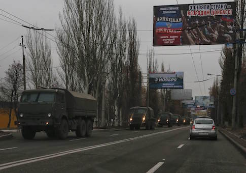 Military trucks are seen through a car window as they drive along a road on the territory controlled by the self-proclaimed Donetsk People's Republic in Makiivka