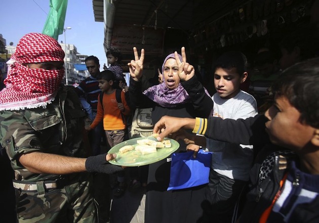 A masked Palestinian distributes sweets as he celebrates with others an attack on a Jerusalem synagogue, in Rafah in the southern Gaza Strip November 18, 2014. Two Palestinians armed with a meat cleaver and a gun killed four people in a Jerusalem synagogue on Tuesday before being shot dead by police, the deadliest such incident in six years in the holy city amid a surge in religious conflict