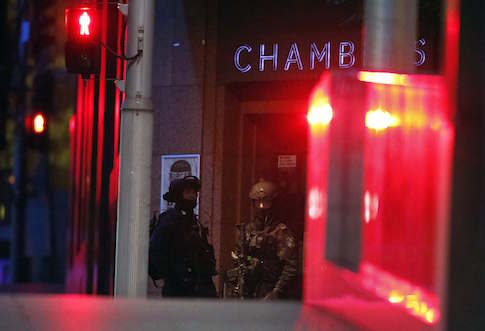 Heavily armed policemen stand guard outside the building containing the Lindt cafe, where hostages are being held, at Martin Place in central Sydney December 16