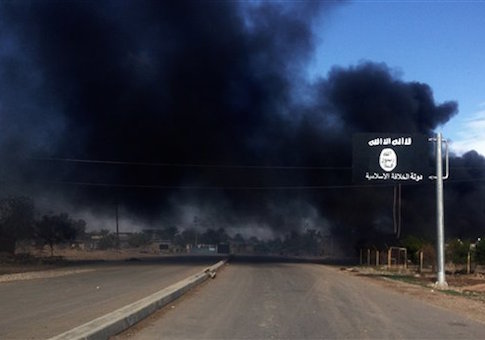 Smoke billows behind an Islamic State group sign