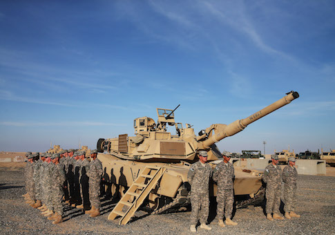 U.S. troops stand at attention next to a Abrams tank waiting for the arrival of Secretary of Defense Chuck Hagel, December 8, 2014 at Camp Buehring, Kuwait