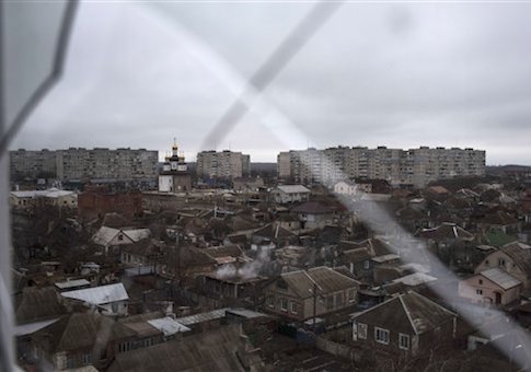 Smoke rises from a destroyed house, in foreground center, damaged in Saturday's shelling at Vostochniy district of Mariupol, Ukraine, Monday, Jan. 26, 2015