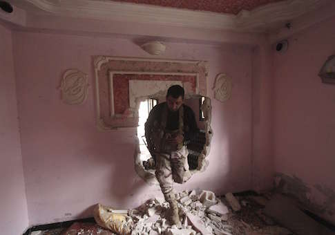 A rebel fighter of al-Jabha al-Shamiya (the Shamiya Front) moves through a hole in a wall inside a house north of Handarat camp in Aleppo, after the group said they took control of the area from forces loyal to Syria's President Bashar al-Assad, February 8, 2015