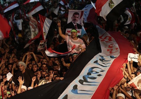 In this Friday, Aug. 2, 2013 file photo, Supporters of Egypt's ousted President Mohammed Morsi hold a large Egyptian national flag as chant slogans against Egyptian Defense Minister Gen. Abdel-Fattah el-Sissi outside Rabaah al-Adawiya mosque
