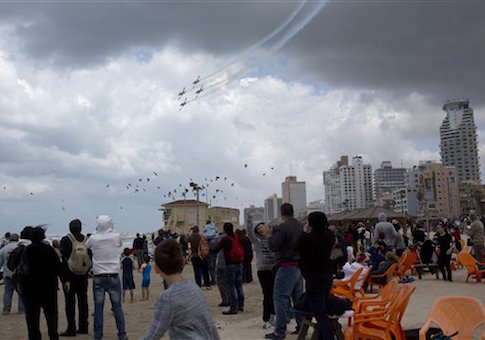 People watch Israeli Air Force planes flying over the Mediterranean sea during Israel's 67th Independence Day, in Tel Aviv, Thursday, April 23