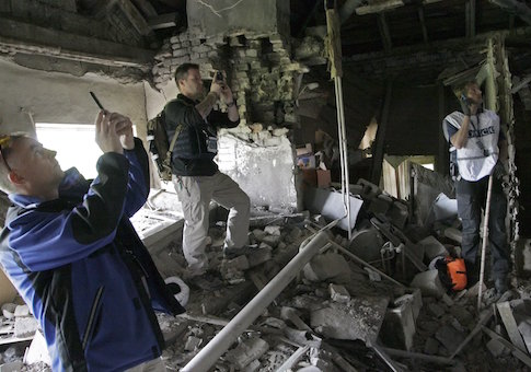 Members of the OSCE work within the ruins of a residential building in Donetsk