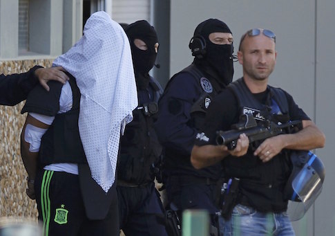 A man supposed to be the suspect who held over an attack against a gas company site is escorted by police officers during investigations in Saint-Priest