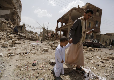 A man and a boy walk at a site hit by a Saudi-led air strike in Yemen's capital