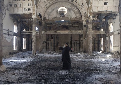 Christian Coptic Priest Father Samuel reacts as he stands inside the burned and heavily damaged St. Mousa church in Minya, Egypt