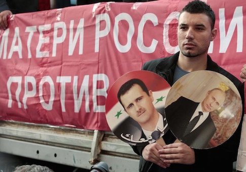A participant hold images of Russian President Putin and Syrian President al-Assad during an anti-war protest organised by the Communist party near the U.S. embassy in Moscow