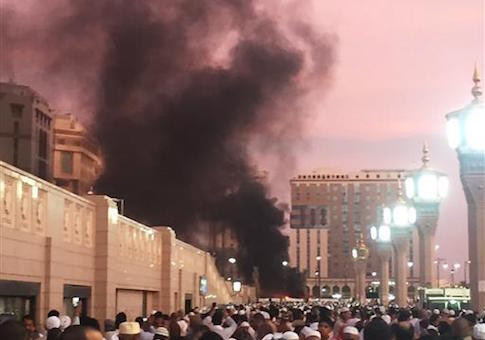 People stand by an explosion site in Medina, Saudi Arabia
