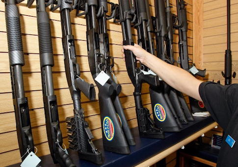 A sales associate takes a gun from a display of shotguns at The Gun Store in Las Vegas