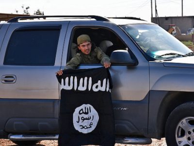 A member of the Syrian pro-government forces holds an Islamic State (IS) group flag after they entered the village of Dibsiafnan on the western outskirts of the Islamist's Syrian bastion of Raqqa