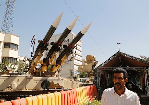 AN Iranian man walks past Sam-6 missiles displayed in the street during a war exhibition
