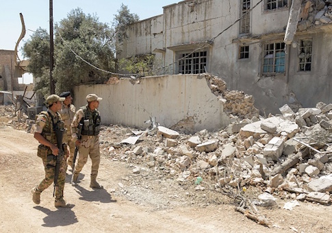 Iraqi soldiers walk down a street in Mosul's western Al-Shifa district on June 15