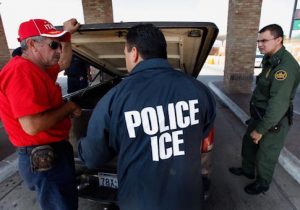 Special agents from Immigration and Customs Enforcement question a man while his vehicle is searched