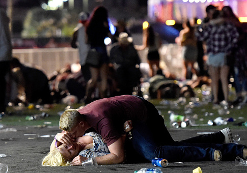LAS VEGAS, NV - OCTOBER 01: A man lays on top of a woman as others flee the Route 91 Harvest country music festival grounds after a active shooter was reported on October 1, 2017 in Las Vegas, Nevada. A gunman has opened fire on a music festival in Las Vegas, leaving at least 2 people dead. Police have confirmed that one suspect has been shot. The investigation is ongoing. The photographer witnessed the man help the woman up and they walked away. Injuries are unknown. (Photo by David Becker/Getty Images)