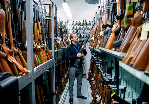 A firearms inspector poses for a photograph with seized and handed in firearms at the storage room of the London Metropolitan Police firearm forensics laboratory
