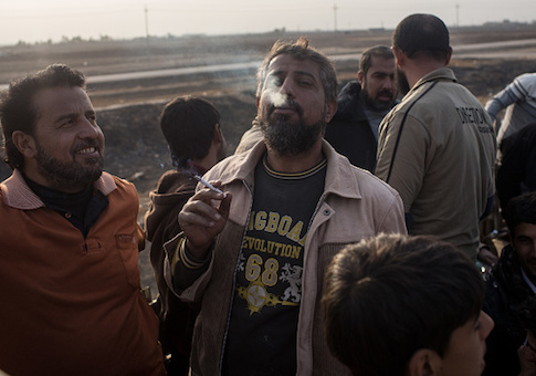 A man smokes his first cigarette after fleeing Mosul