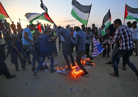 Protesters waving Palestinian flags stamp on burning prints of US flags and President Donald Trump in Gaza