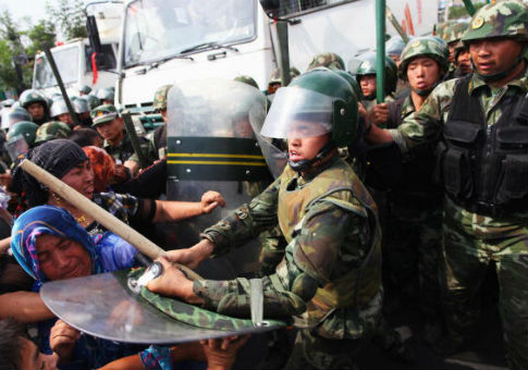 Chinese policemen push Uighur women protesting in Urumqi, capital of Xinjiang region in China