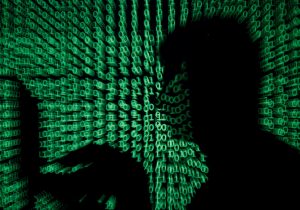 FILE PHOTO: Man holds laptop computer as cyber code is projected on him in this illustration picture