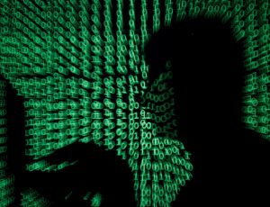 FILE PHOTO: Man holds laptop computer as cyber code is projected on him in this illustration picture