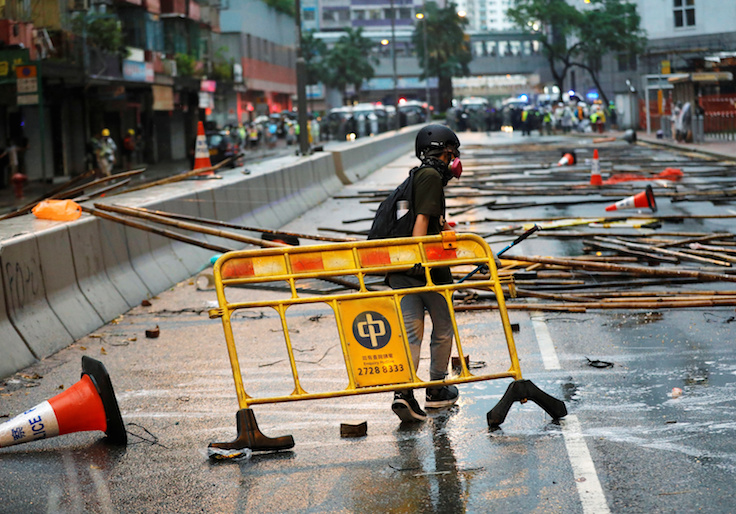 An anti-extradition bill protester carries a barricade for blocking the road during a protest in Hong Kong