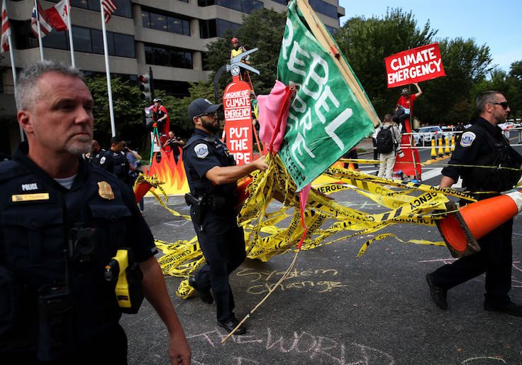 Police carry signs used by protesters and police tape as activists advocating for new policies to combat global climate change close an intersection