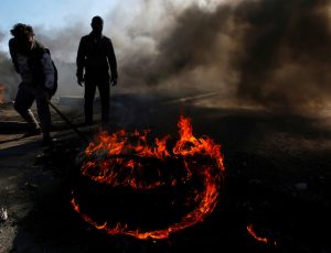 Iraqi demonstrators burn tires to block a road during ongoing anti-government protests in Najaf