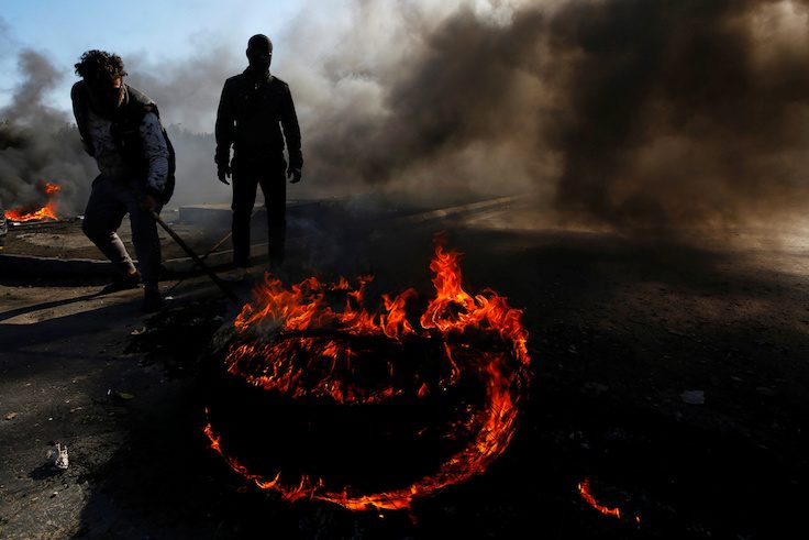 Iraqi demonstrators burn tires to block a road during ongoing anti-government protests in Najaf